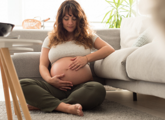 A pregnant woman sitting on the floor.
