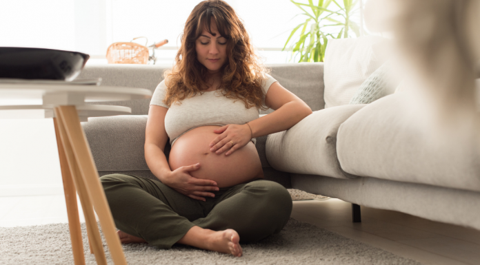 A pregnant woman sitting on the floor.