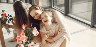 A woman holding flowers and hugging a girl.