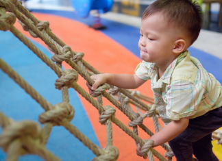 a baby climbing a rope at gym class.