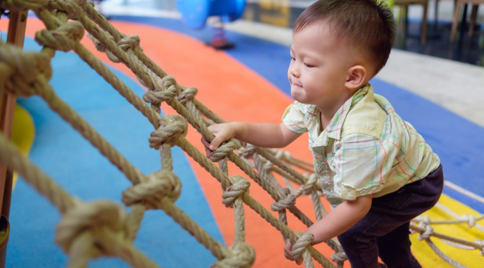 a baby climbing a rope at gym class.