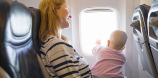 A woman holding a baby on a plane.