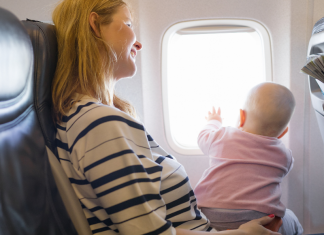 A woman holding a baby on a plane.