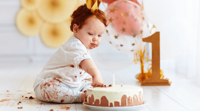 A baby with a first birthday cake.