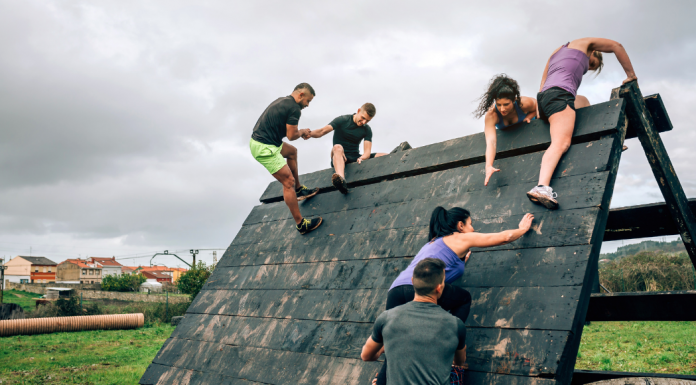 People climbing a large wall in an obstacle course race.
