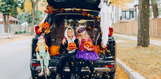 Two kids dressed in Halloween costumes sitting in the trunk of a car.
