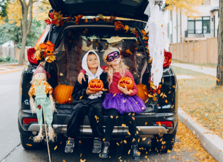 Two kids dressed in Halloween costumes sitting in the trunk of a car.