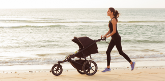 A woman running with a stroller on the beach.
