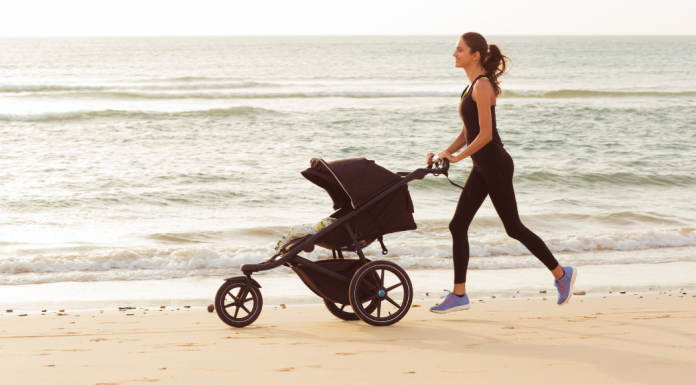 A woman running with a stroller on the beach.