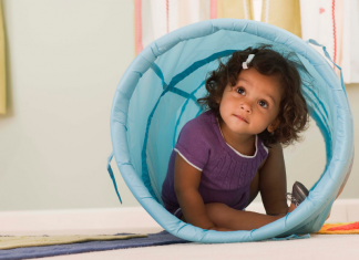 A toddler girl playing in a tunnel.