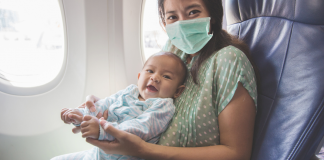 A mom holding a baby on an airplane.