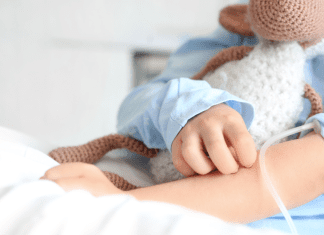 A child holding a stuffed animal in a hospital bed.