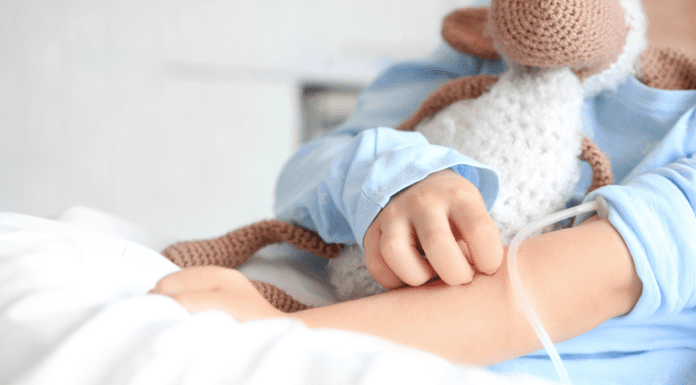 A child holding a stuffed animal in a hospital bed.
