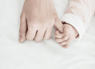 A baby holding onto a mom's pinky.