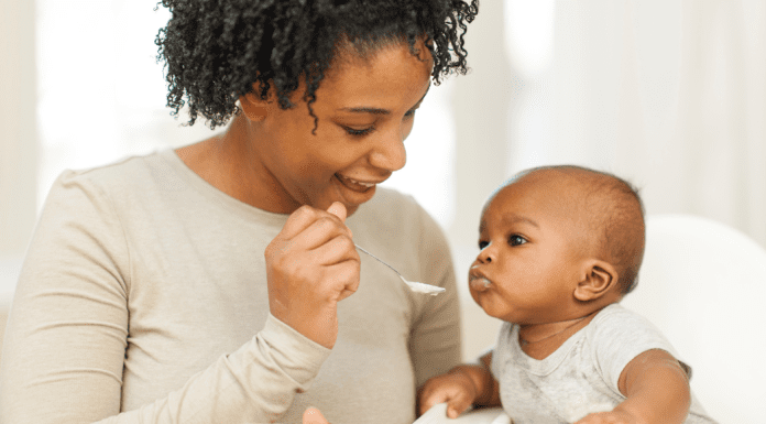 A woman feeding her baby with a spoon.