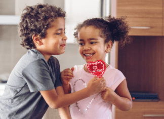 A boy and girl holding a lollipop Valentine.