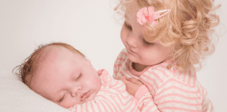 A girl holding her baby sister.
