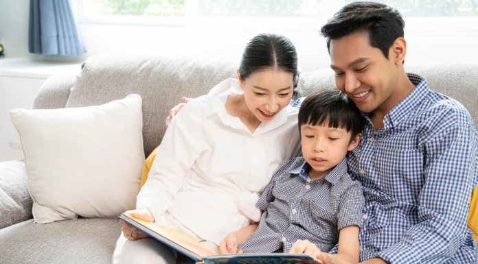 A mother and father reading a book to their son.
