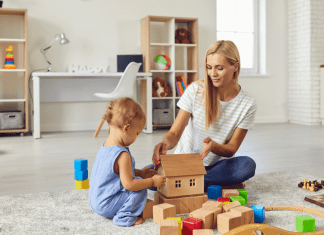 A babysitter playing blocks with a little boy.