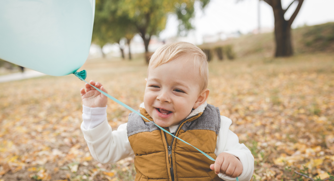 A toddler holding a balloon.