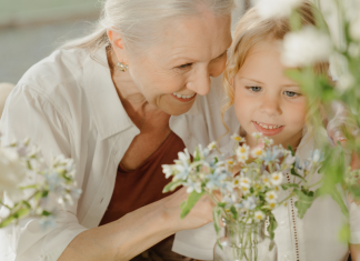 A grandmother picking flowers with her granddaughter.