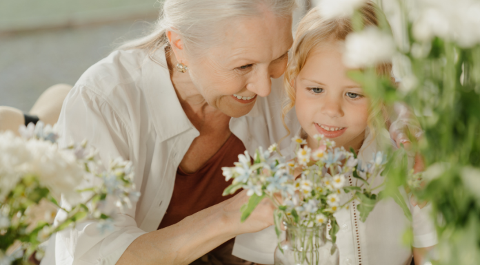 A grandmother picking flowers with her granddaughter.