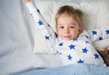 A three-year-old boy stretching in bed.