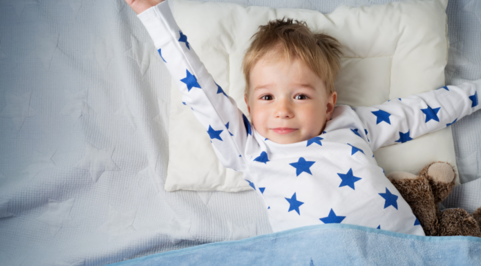 A three-year-old boy stretching in bed.
