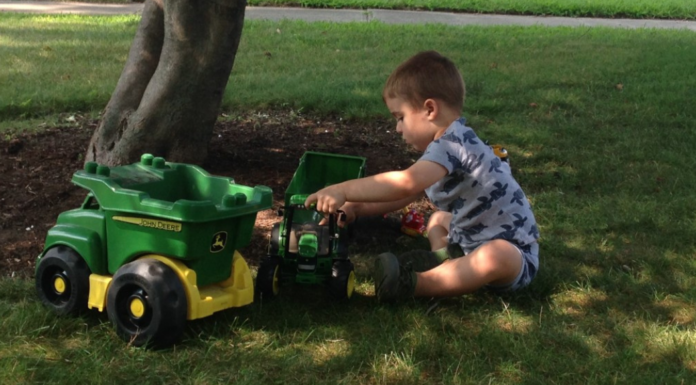 A boy playing with his trucks in the backyard.