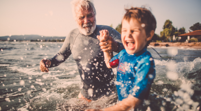 A grandfather playing with his grandson in the ocean.