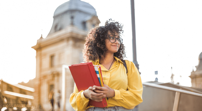 A girl holding books on a college campus.