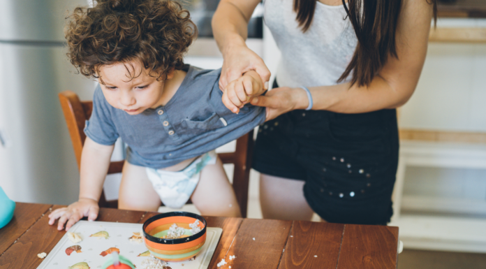 A mom trying to clean up her toddler boy.