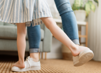 A mom dancing with her child's feet on top of her own.