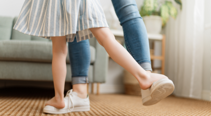 A mom dancing with her child's feet on top of her own.