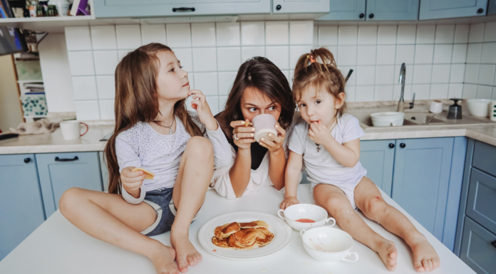 A mom drinking coffee while her kids sit on the counter while thinking about the universal truths of motherhood.