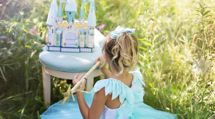 A girl dressed like a princess playing with the Frozen castle.