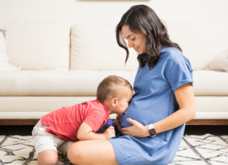 A boy kissing his mom's belly during her first trimester.