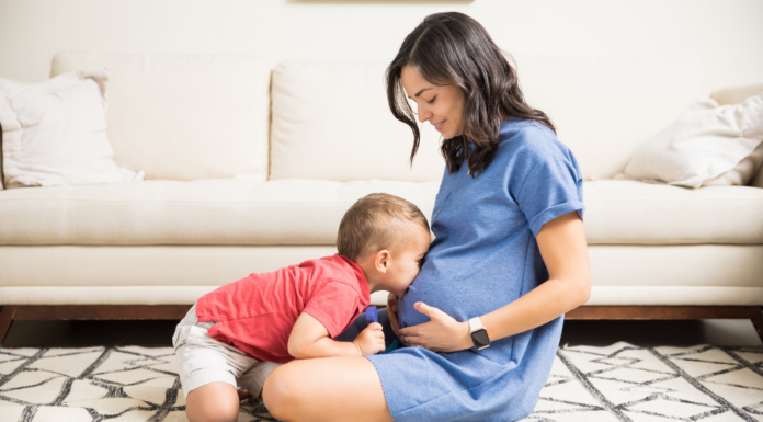 A boy kissing his mom's belly during her first trimester.