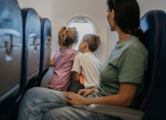 We’re Leaving On a Jet Plane: Toddler Edition A mom and kids sitting on a plane looking out the window.