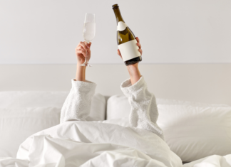All By Myself: Time For a Solo Vacation A woman holding champagne in a hotel bed.