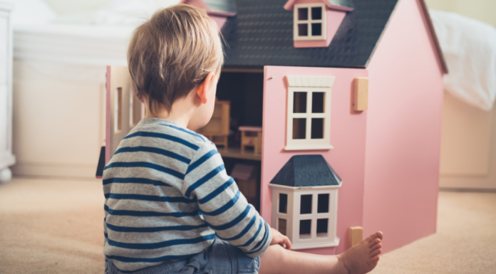 A boy playing with a dollhouse.