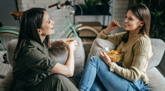 Two friends sitting on a couch talking.
