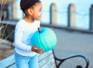 Teal Pumpkins…What’s This All About? A girl holding a teal pumpkin.
