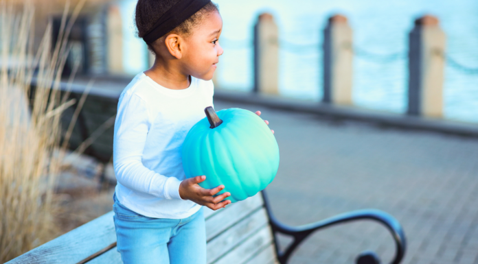 A girl holding a teal pumpkin.