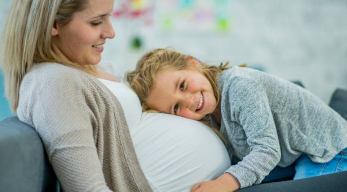 A daughter hugging and holding her mom's pregnant belly.