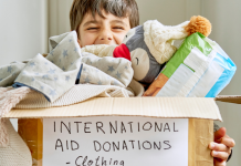 A child holding a box of international aid donation items.