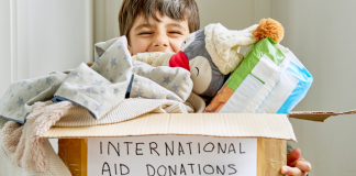 A child holding a box of international aid donation items.