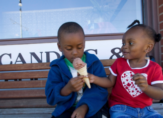 A girl sharing her ice cream with her brother.