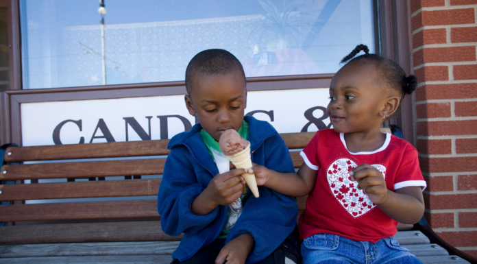 A girl sharing her ice cream with her brother.