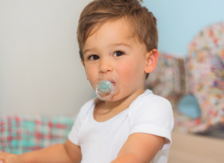 A boy with a pacifier in his mouth.